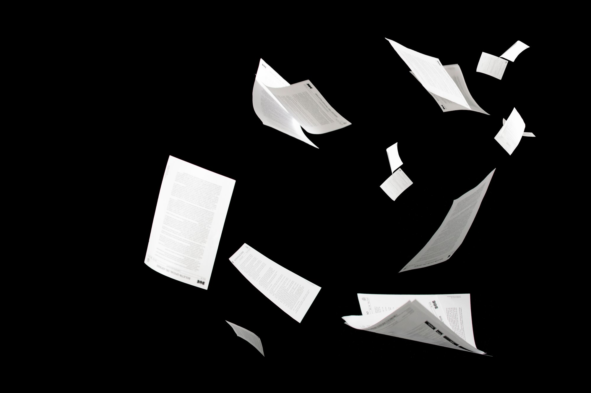 White paper pages drifting through the air, set against a black background.